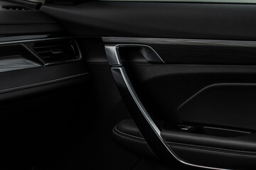 Obraz na płótnie Canvas Modern car interior door handle close up. Metallic Car door opener handle inside.