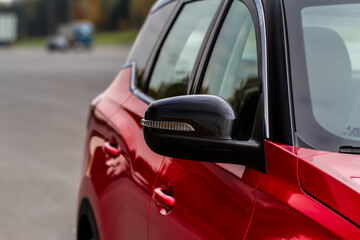 Close up front view of car side mirror. Front rear view mirror on the car window. Car exterior details. Red car mirror.