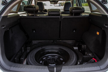 Spare wheel in the trunk of a modern car. Jack lifting and a spare tire in rear of car.