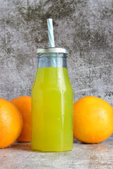 Vertical shot, glass bottle with refreshing orangeade, 
stone base in light colors and copy space.