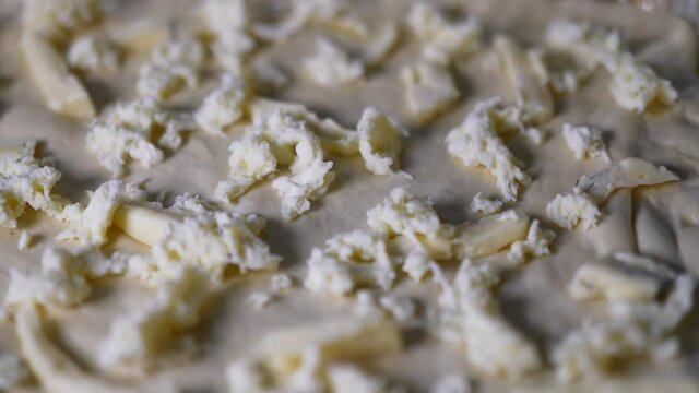 Closeup dolly shot of an organic traditional Italian pizza seasoned topped with cheese on the dough with red tomato sauce on it.