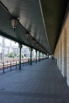 Travel expectation. Krakow railway station, old empty train platform, track line corridor with vintage lanterns, metal columns, green charismatic curved roof. Poland