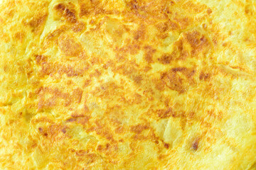 Background, food texture, a potato omelette with onion, typical of Spain. Zenith view.