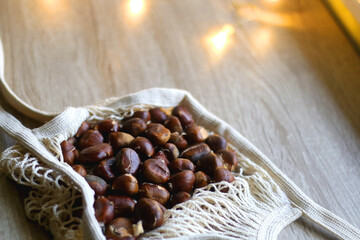 Reusable mesh bagfilled with fresh chestnuts. Selective focus.