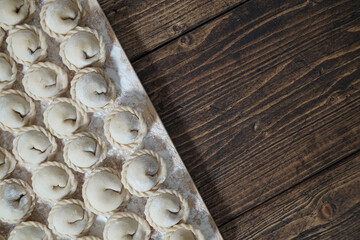 Meat or vegeterian dumplings, pelmeni on a wooden board. Russian national food. Close up top view with copy space.