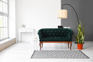 Interior of light living room with green sofa, houseplant and standing lamp