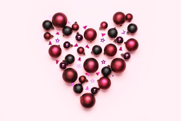Heart shape made of Christmas balls on pink background