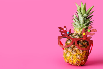 Funny pineapple in Christmas glasses on pink background