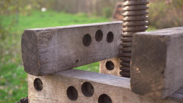 Close up men's hands assemble a wooden press for harvesting apple juice cider alcohol. Pressing fresh apples in bucket to produce in village. Fruit packaging warehouse, food processing 4k