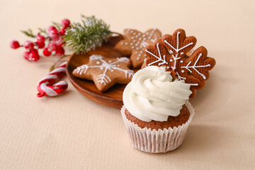 Tasty Christmas cupcake with gingerbread cookies on beige background