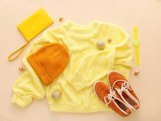 Warm sweater, shoes, accessories and Christmas balls on color background