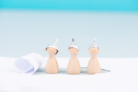 Three wooden figures wearing an alu hat, conspiracy theories, tin foil, symbolic