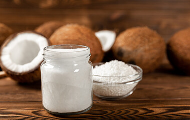 coconuts, coconut flakes and coconut oil on a wooden background. Close-up.