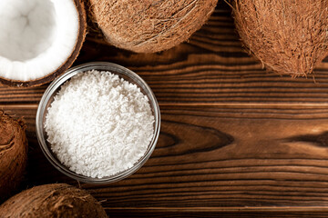 Coconut flakes in a bowl, coconuts on a wooden background. Close-up. copy space.