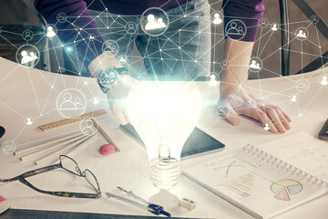 Double exposure of man's hands holding and using a digital device and bulb hologram drawing. Idea concept.