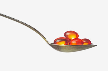 Orange transparent capsules with vitamins or medicine in spoon isolated