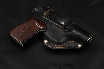 Pistol in leather holster on the black table