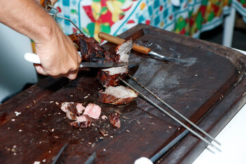 Detail of waiter slicing barbecue