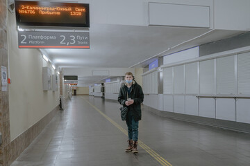 a young man in a medical mask, in a public corridor, heading for a train station