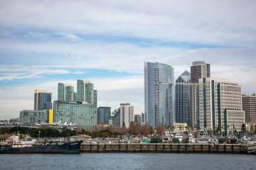 Fototapeta na wymiar A View of the San Diego Embarcadero Downtown Skyline with One America Plaza Looking at the Skyline and the USS Midway Museum Moored to the Dock