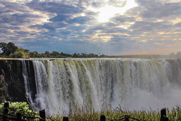 Beautiful cloudy landscape with morning sun rays over Victoria Falls.