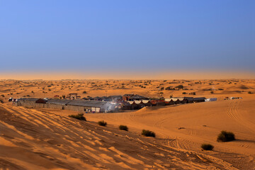 Fototapeta na wymiar Bedouin village in the desert, in the sand dunes. Orange desert sand landscape
