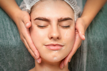 Naklejka premium Spa facial skincare. Close-up of a young caucasian woman getting spa moisturizing face massage treatment at beauty spa salon