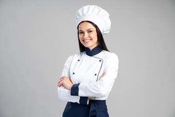 Chef woman wearing uniform and cap standing arms crossed and posing over isolated grey background....