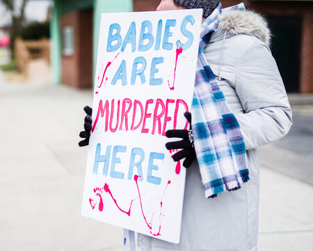 person holding an abortion protest sign that says BABIES ARE MURDERED HERE