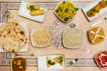 Set of Indian food dishes with various flavors curry, garlic naan, and basmati rice with cheese roll