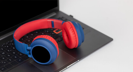 Laptop with wireless headphones on white background