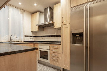 Kitchen with light wood cabinets, large stainless steel fridge in a vacation rental apartment