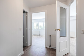 Empty room with aluminum window, white aluminum radiator and wardrobe with mahogany doors and gold handles