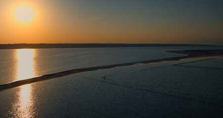 Calm ocean surface reflecting bright yellow sunlight at summer evening. 