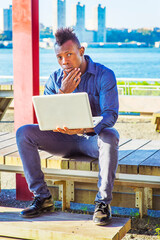 Man Working on Site. Wearing a blue shirt, pants, leather shoes, a hand touching his chin, a young...