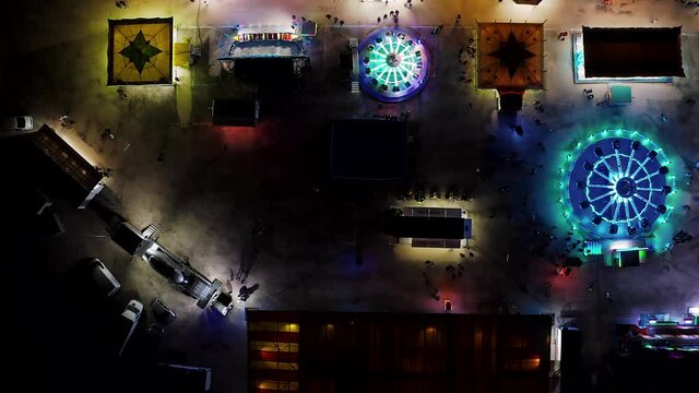 State fair at night time aerial view. Drone flight over blinking neon lights with carousel ride at carnival in Portugal. 