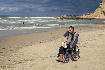 Disabled man sitting on a wheelchair playing paddle ball on the beach