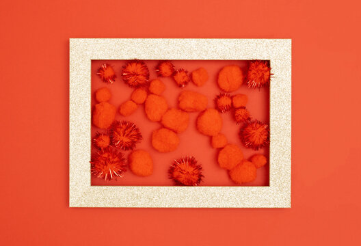Empty gold picture frame with pom-poms on red background. Romantic Valentines day composition. Flat lay. Love concept.