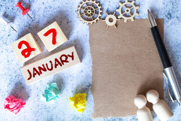 January 27. Date of January month. Number Cube with a flower and notebook on Diamond wood table for the background