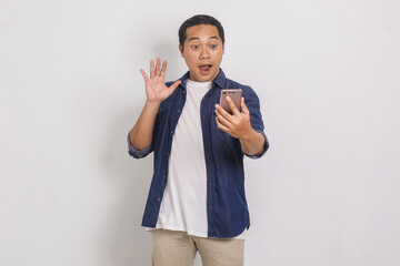 Portrait of handsome asian man being surprised looking at his mobile isolated on white background 