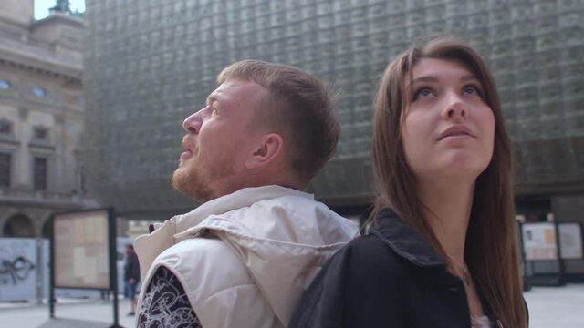 Circular motion of the camera around the couple on a date. They look around, orientate themselves in the city. Focus on buildings.