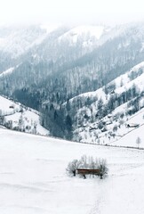 Fototapeta na wymiar Barn in snow against snowcapped mountain in a foggy winter day