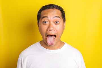 Close-up portrait of asian man with reproachful expression, mocking, sticking out tongue isolated...