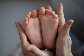 Mother holding little baby feet, selective focus. Newborn, love and care concept 