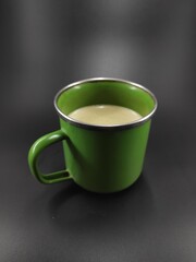 Photo of a glass of green cup containing cappuccino coffee isolated on black background, Not Focus
