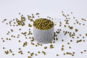 mung bean in plastic spoon on a pile of mung beans on white background studio shot