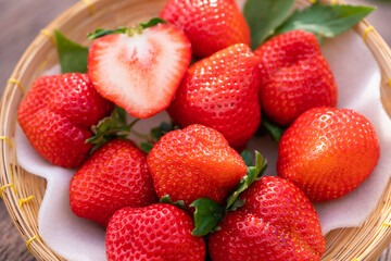 Fresh organic juicy strawberries in a wicker tray on a brown shabby wooden table