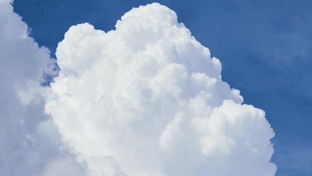Timelapse of white puffy cumulus clouds forming on summer blue sky. Moving and changing cloudscape weather