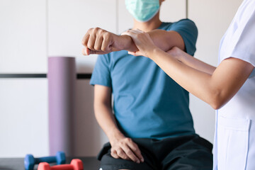 Physiotherapist woman training with man patient using dumbbells in clinic,Physical therapy concept