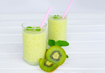 Kiwi yogurt fruit juice smoothie and green kiwi juice drink healthy, delicious taste in a glass for weight loss on a white wooden background.
